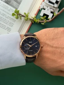ساعت Q&Q A12A-008 با بند چرمی قهوه‌ای روی مچ دست